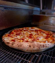 A pepperoni pie coming off the oven deck